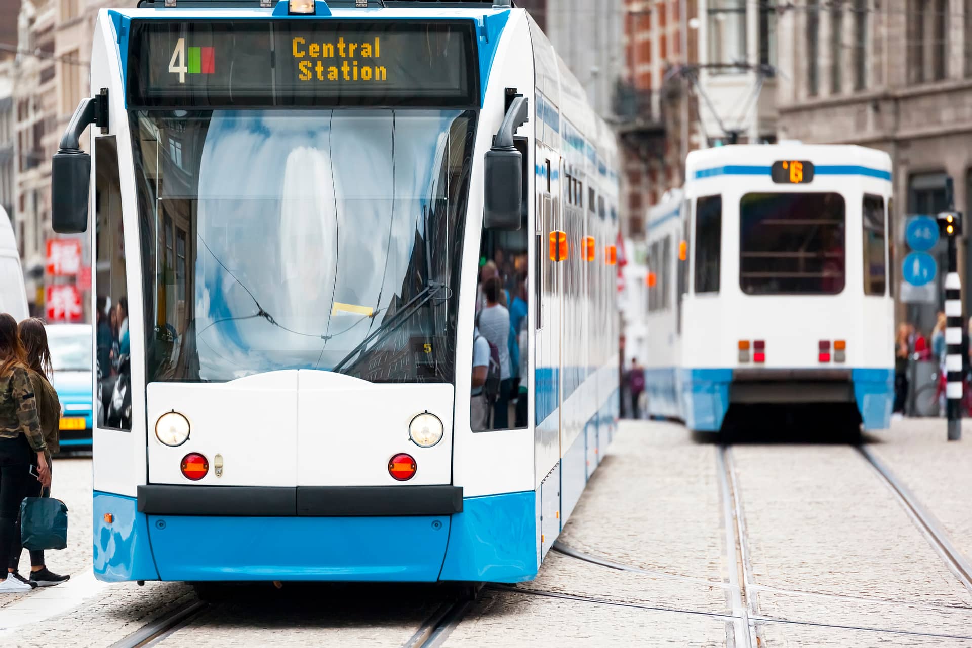Front view of a blue and white tram on a city street, display reads 'Central Station' with route number 4.